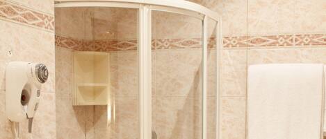 A bathroom with a glass-enclosed shower, a toilet, and a towel rack.