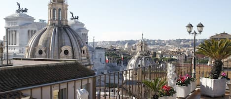 A rooftop terrace with a view of historic buildings, including a dome and statues.