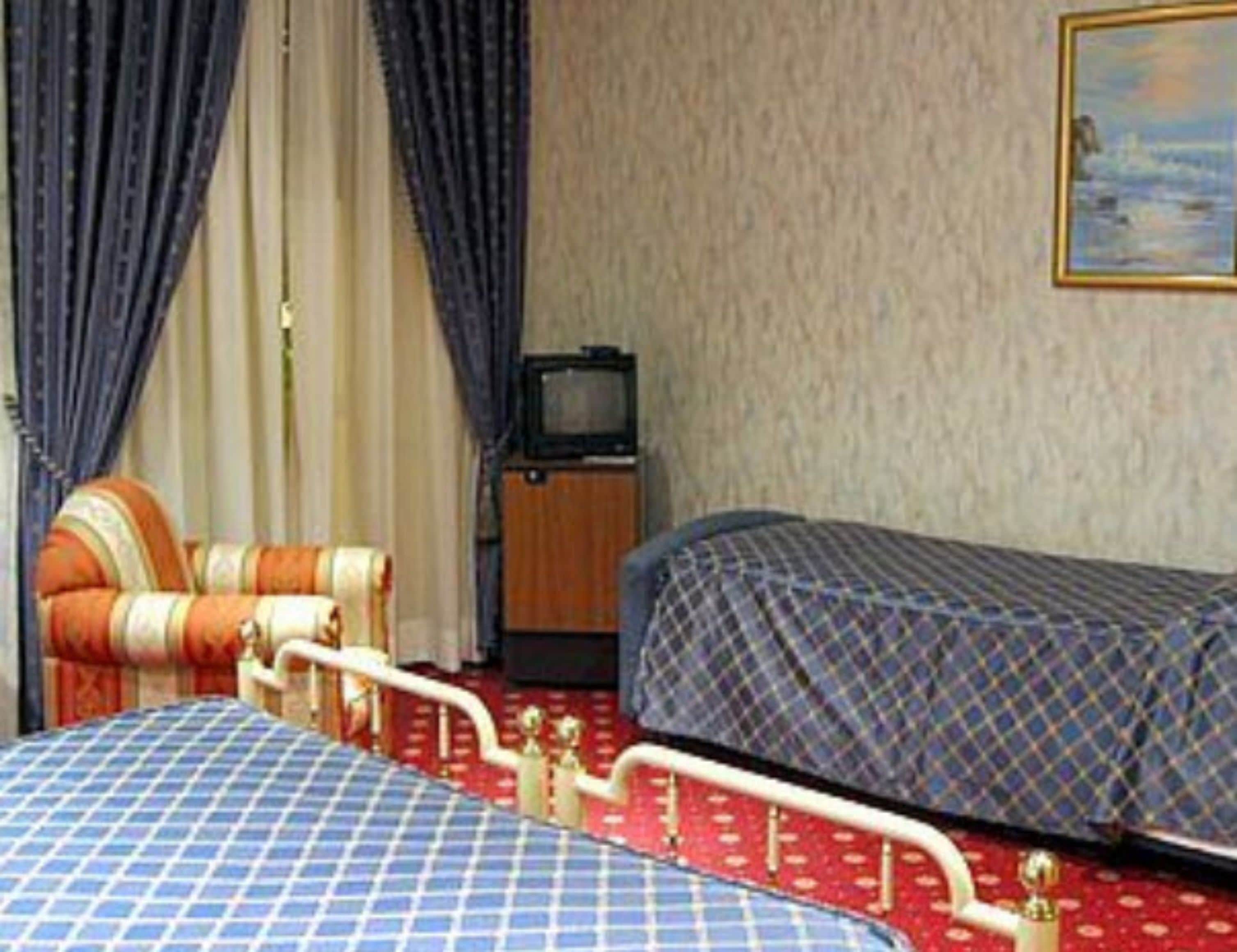 A bedroom with two beds, a television, and a small cabinet.