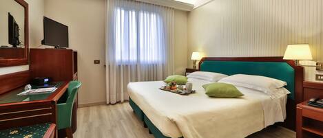 Una habitación de hotel con cama, escritorio, silla y televisor.