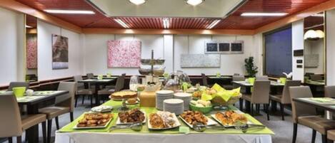 A spacious dining area with multiple tables and chairs, a buffet setup with various dishes, and a modern ceiling design.