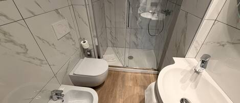 Un baño moderno con inodoro, bidé, lavamanos y ducha.