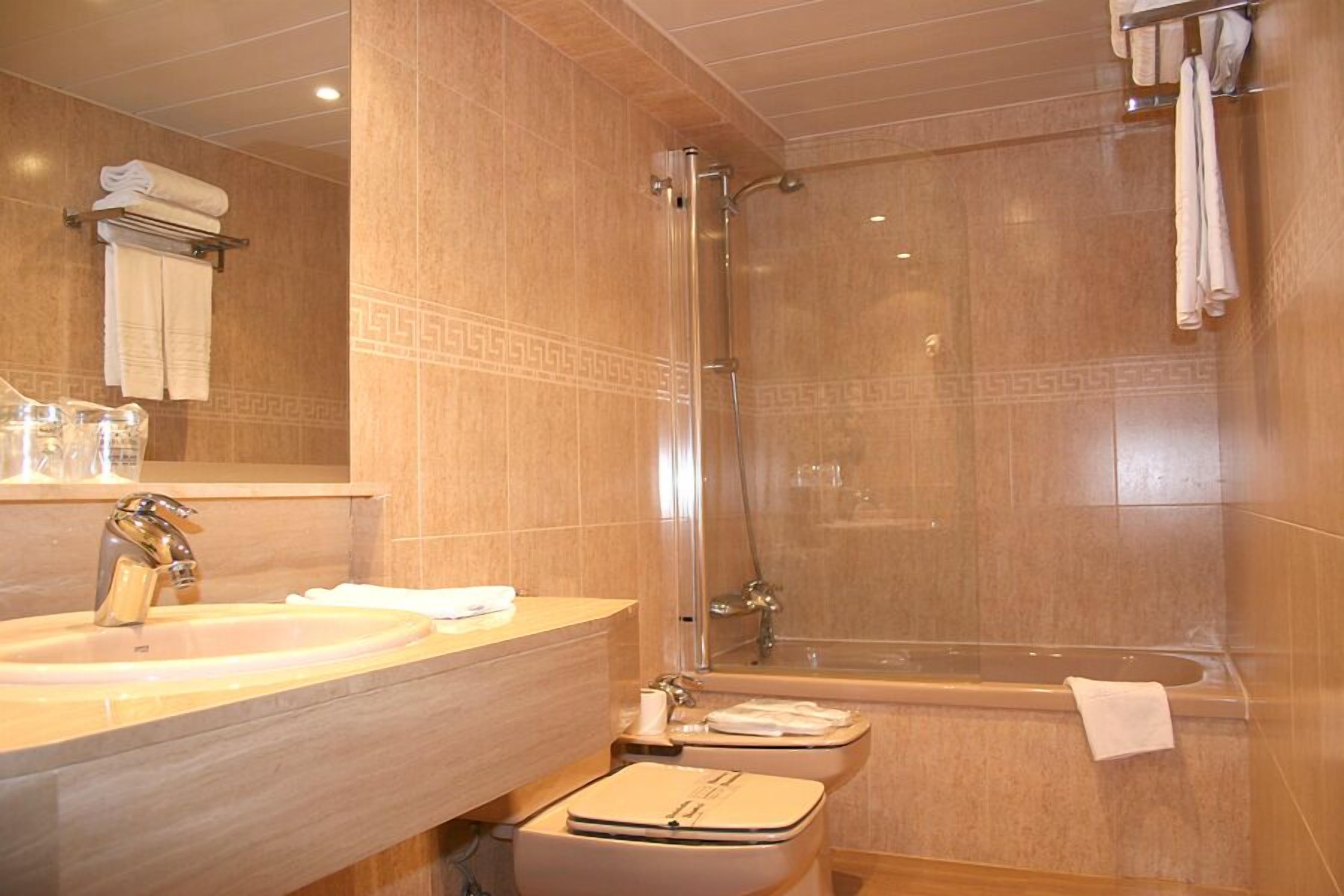 A bathroom with a sink, mirror, shower, and bathtub.