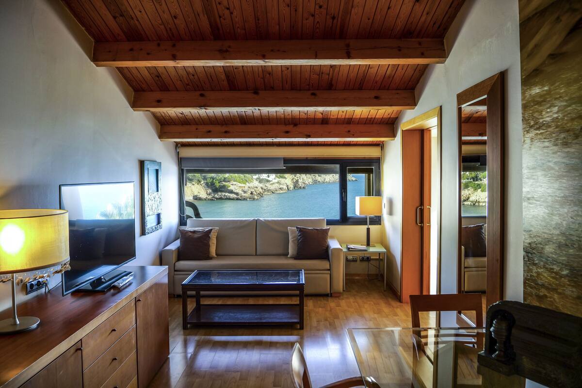 A modern living room with a wooden ceiling, a sofa, a coffee table, and a TV.