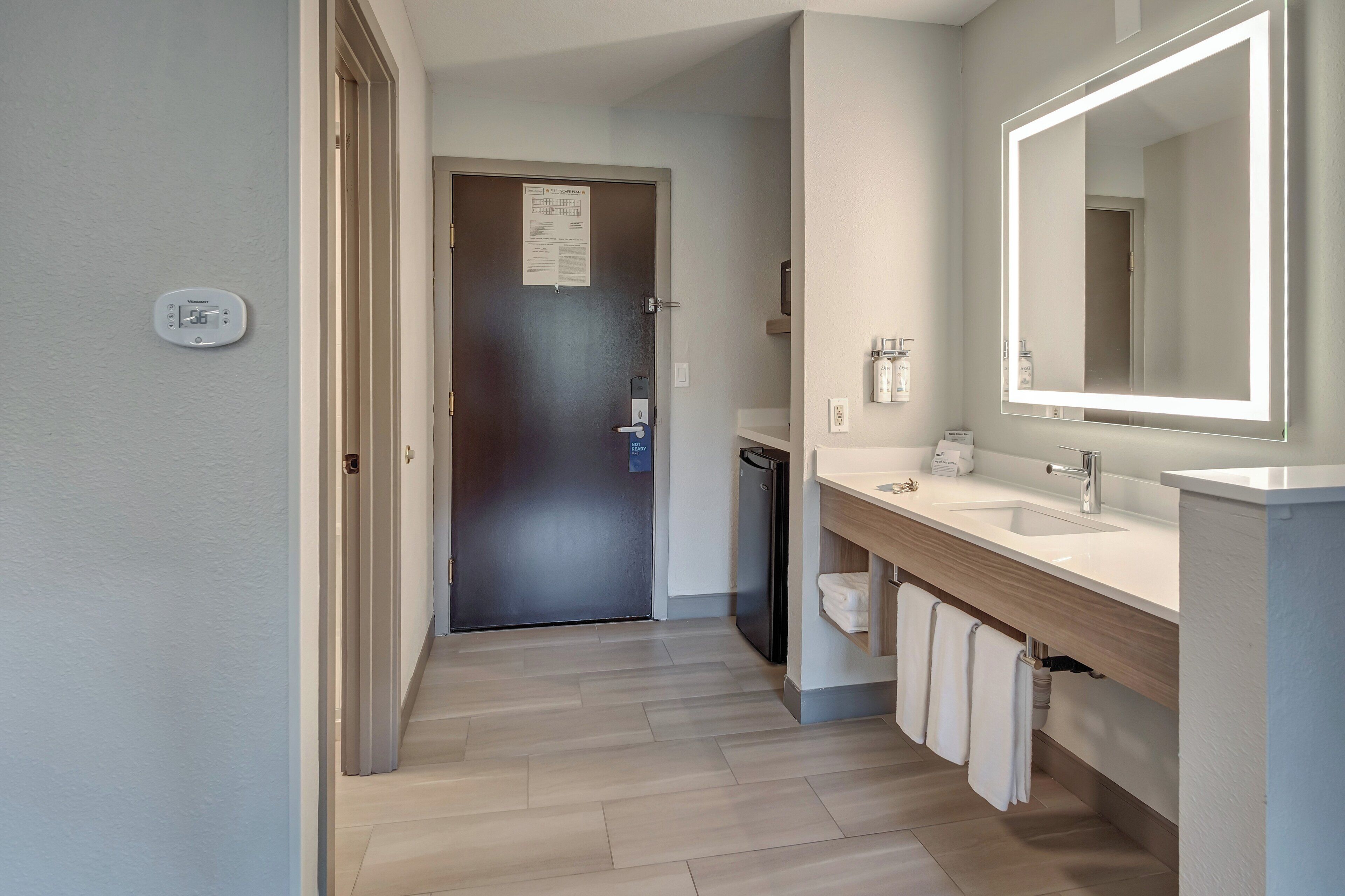 A modern bathroom with a large mirror, two sinks, and a wooden vanity.