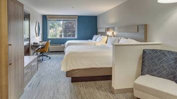A hotel room with two beds, a desk, a chair, and a sofa.