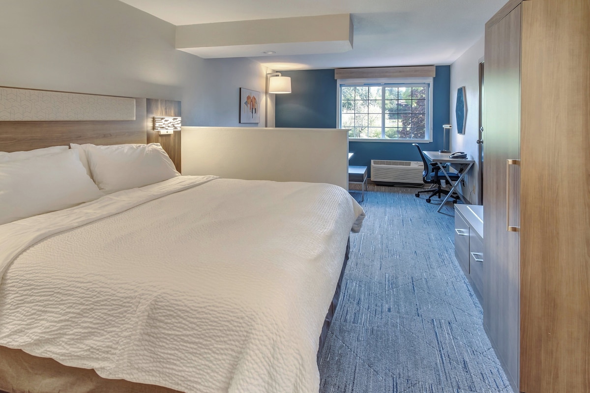 Quarto de hotel com uma cama grande, uma mesa e uma cadeira.