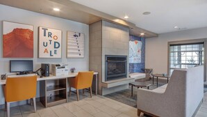 Een moderne woonkamer met een open haard, een eethoek met oranje stoelen en kunstwerken aan de muur.
