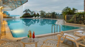 An indoor swimming pool with clear blue water, surrounded by lounge chairs and a covered seating area.