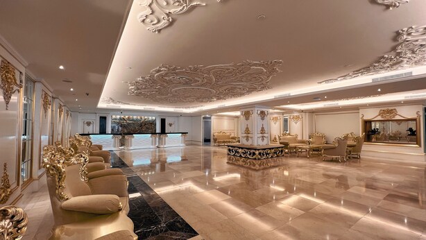 A luxurious lobby with ornate ceiling decorations, a reception desk, and plush seating areas.