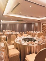 Un salón de banquetes con mesas redondas dispuestas para comer, cubiertas con manteles color beige y sillas a juego.