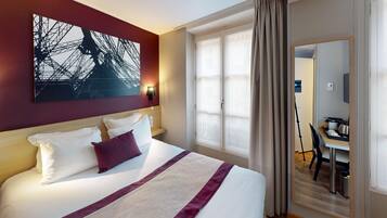 A hotel room with a large bed, a desk, and a chair.