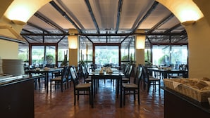 A spacious dining area with high ceilings and large windows, featuring a central table with chairs and a buffet table on the right. - Dom Pedro Marina (Loulé)