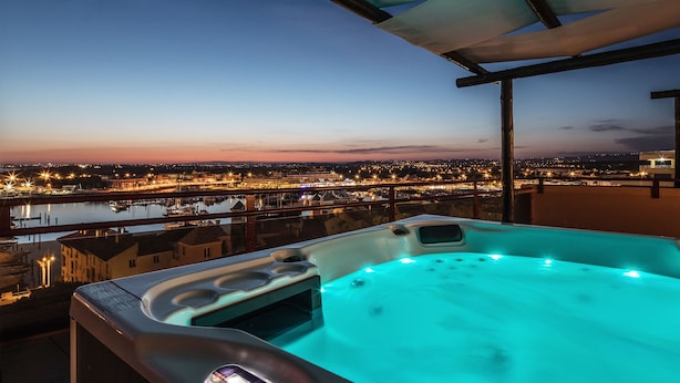 A hot tub with a panoramic city view at dusk. - Dom Pedro Marina (Loulé)