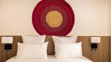 A hotel room with a bed, two bedside lamps, and a circular wall hanging.