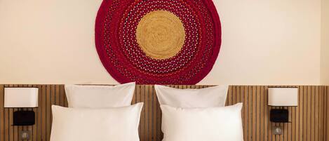 A hotel room with a bed, two bedside lamps, and a circular wall hanging.