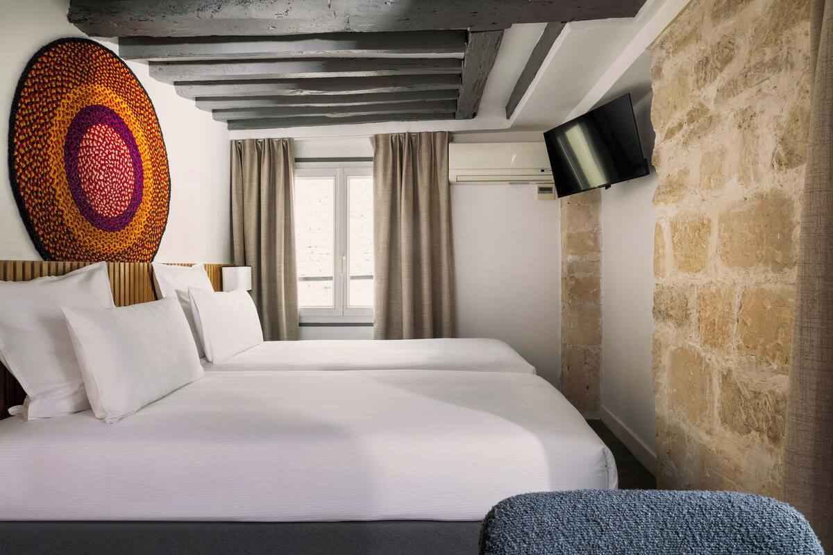 Een moderne hotelkamer met een groot bed, een flatscreen televisie aan de wand en een accentmuur van steen.