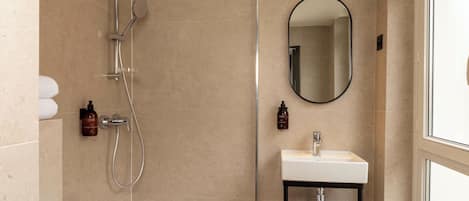 Un baño moderno con ducha, lavamanos y espejo.