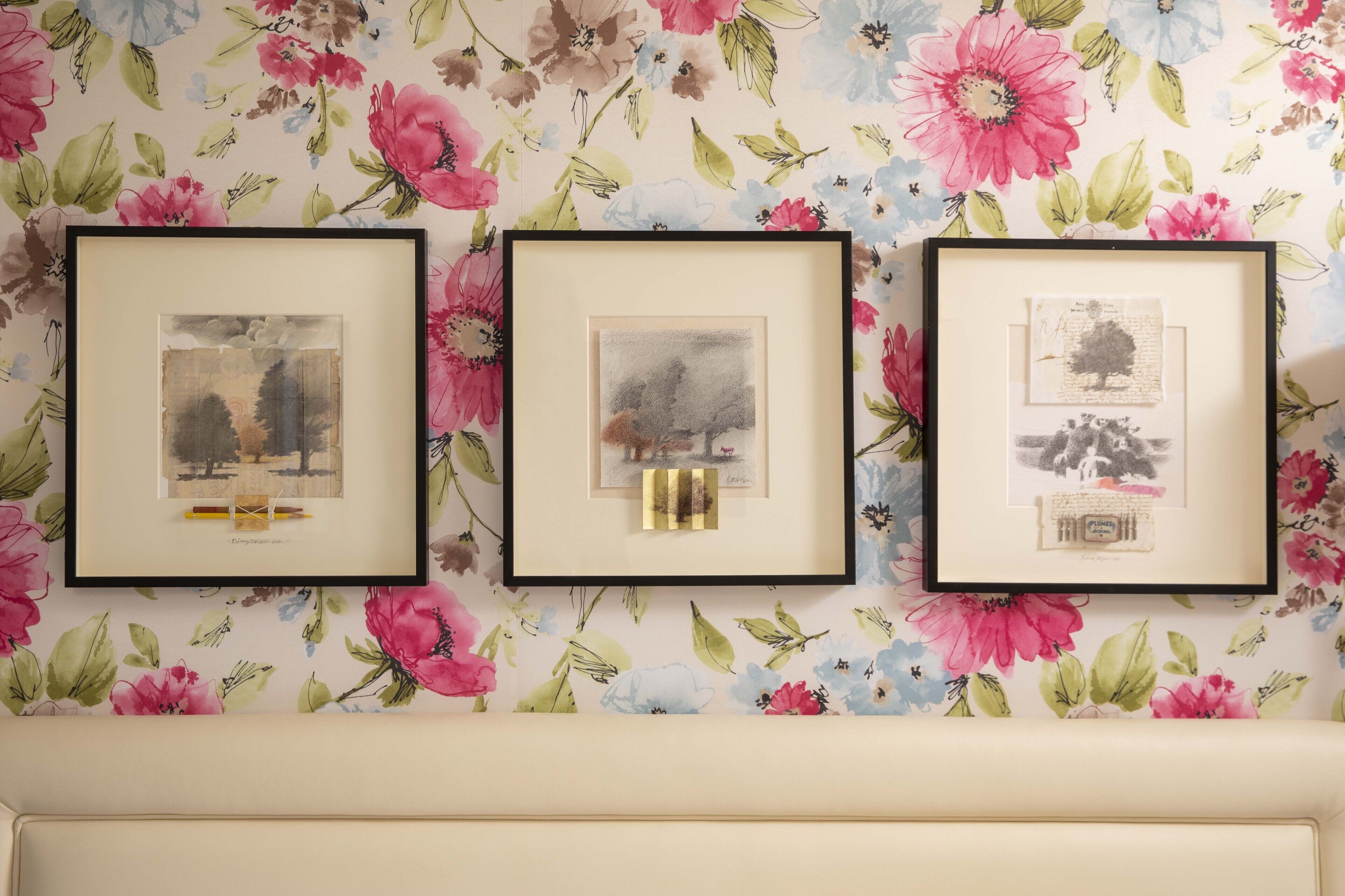 Three framed artworks on a floral wallpaper background.