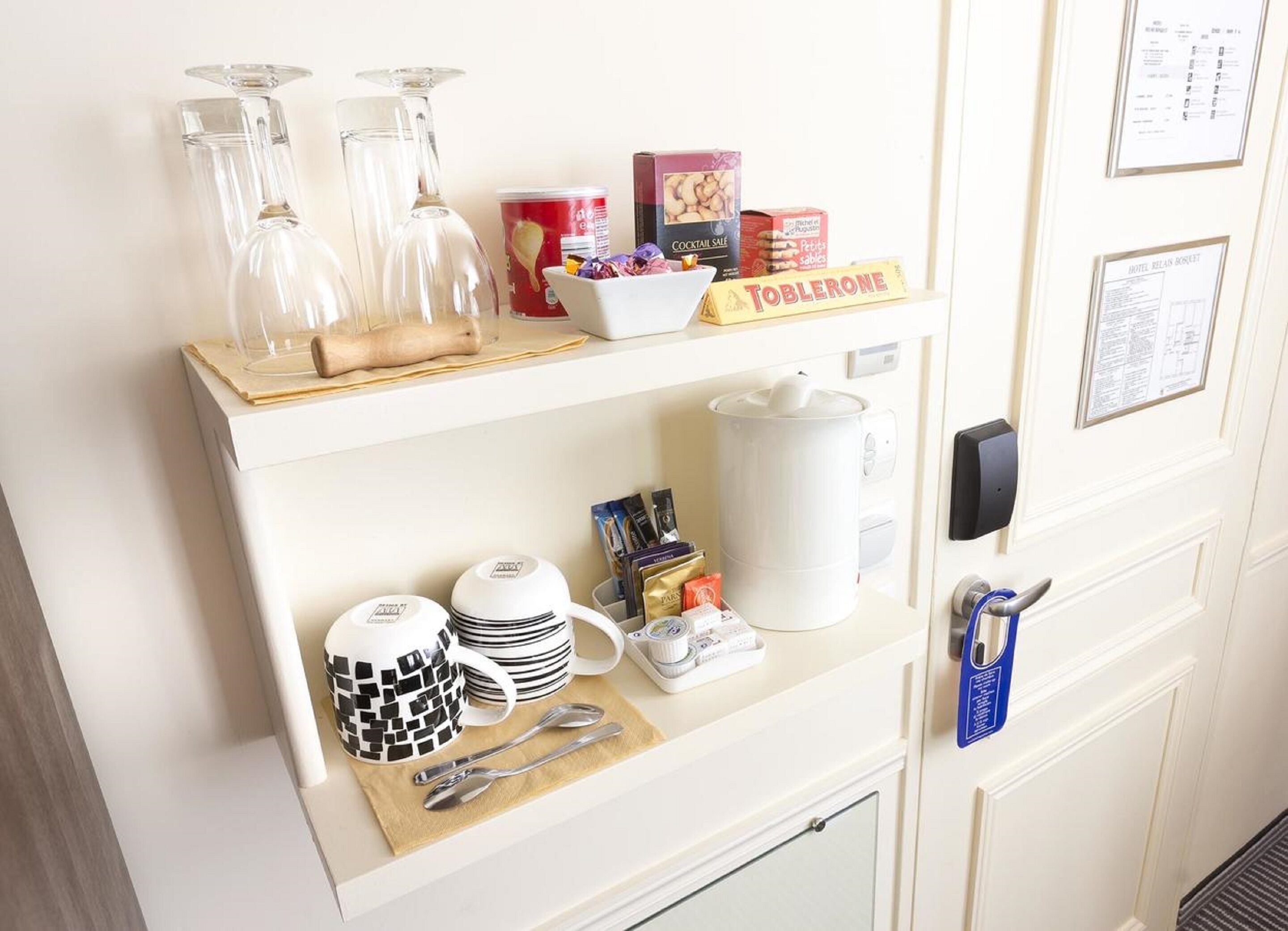 Eine Minibar mit Kaffeemaschine, Tassen, einer Schale mit Snacks und einer Toblerone.