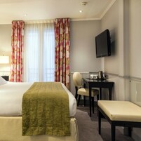 Une chambre d’hôtel équipée d’un lit, d’un bureau, d’une chaise et d’un téléviseur.