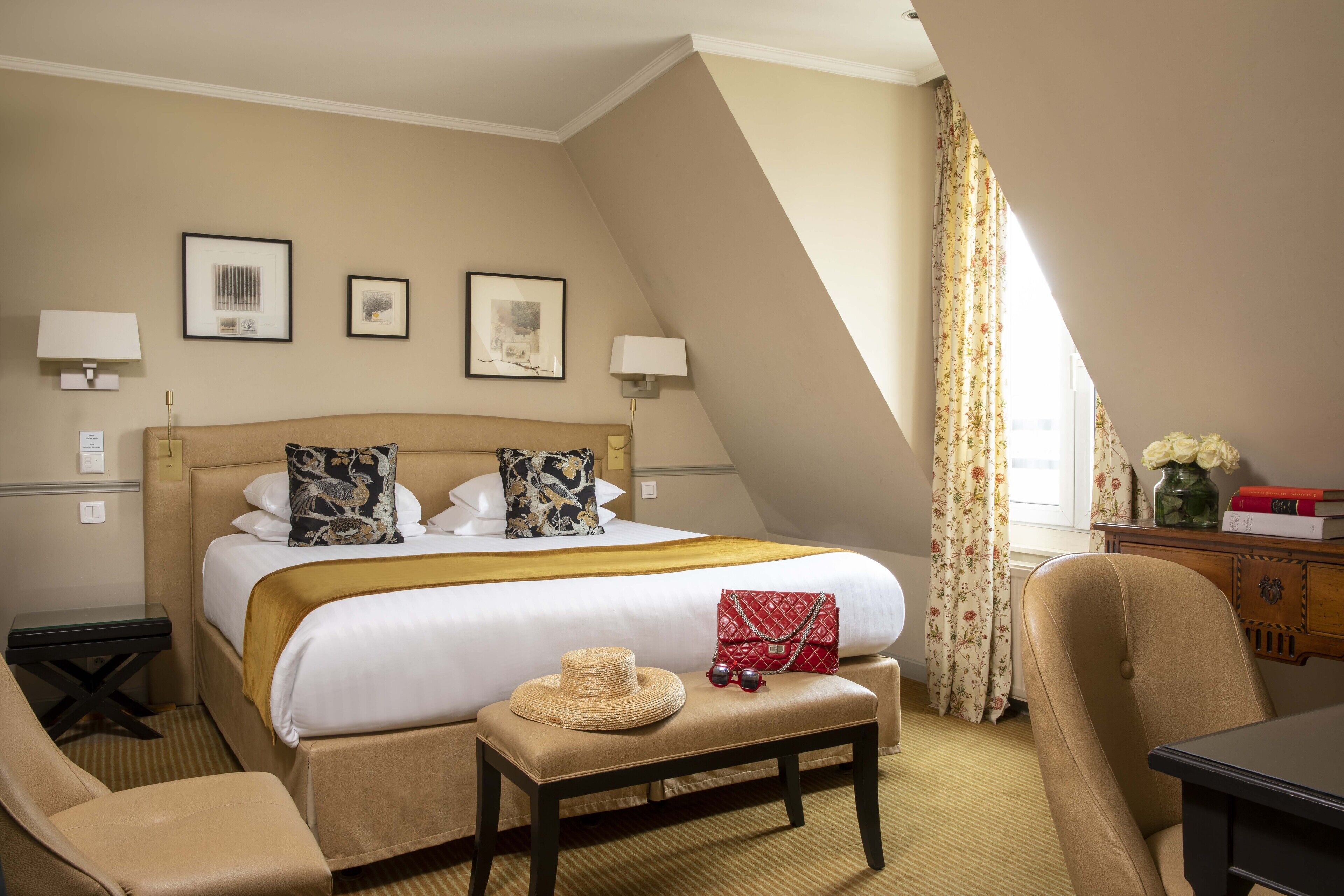 A hotel room with a bed, bedside tables, a desk, a chair, and a window with curtains.
