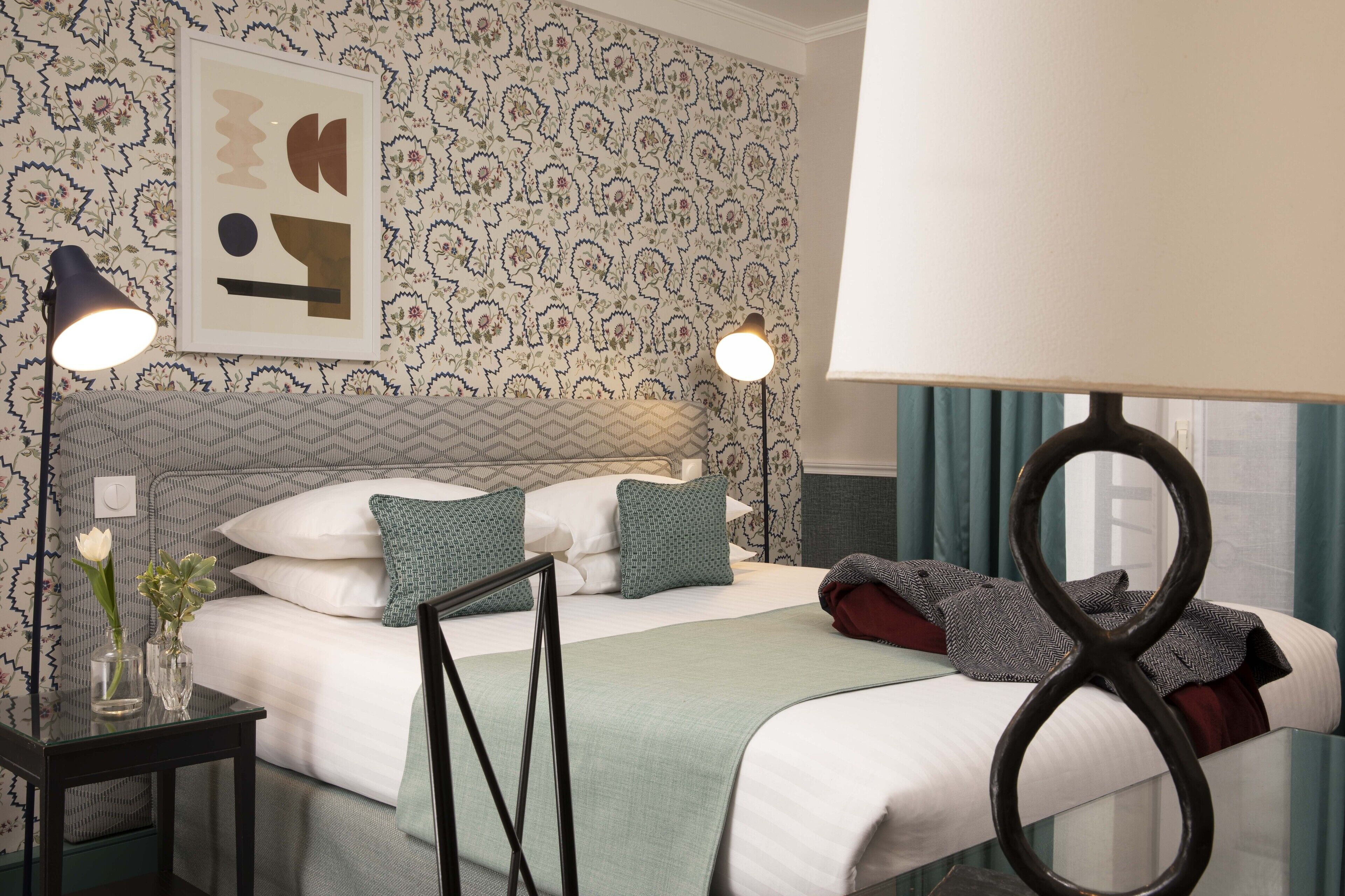 A neatly arranged hotel room with a bed, bedside tables, a framed picture, and a window with curtains.
