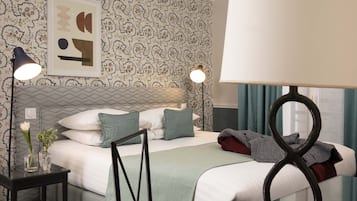 A neatly arranged hotel room with a bed, bedside tables, a framed picture, and a window with curtains.