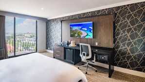A hotel room with a large bed, a desk with a computer, a TV mounted on the wall, and a view of the city through large windows. - Hotel Lucerna Ciudad Juarez (Ciudad Juárez)
