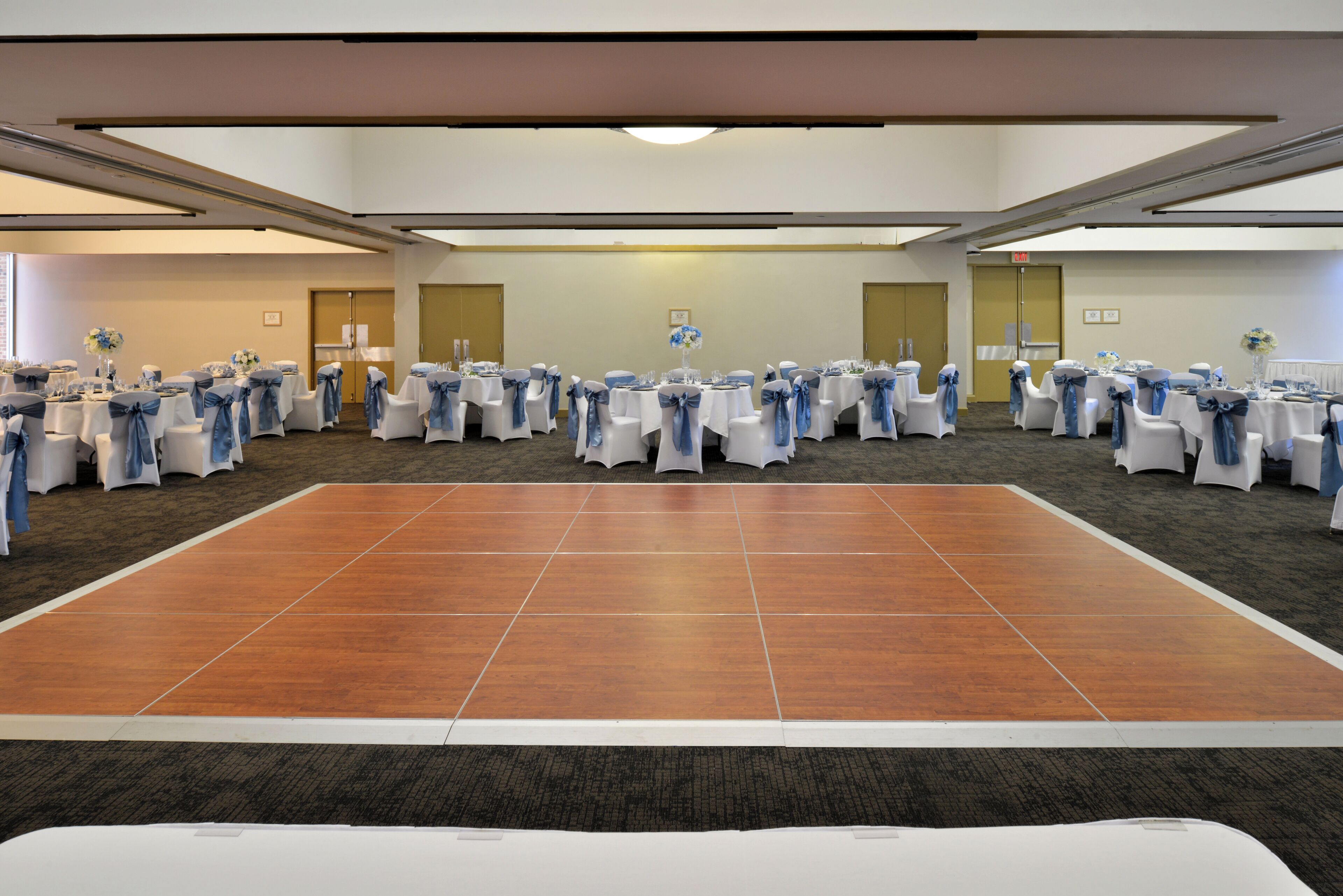 A conference room with round tables, chairs, and a dance floor.