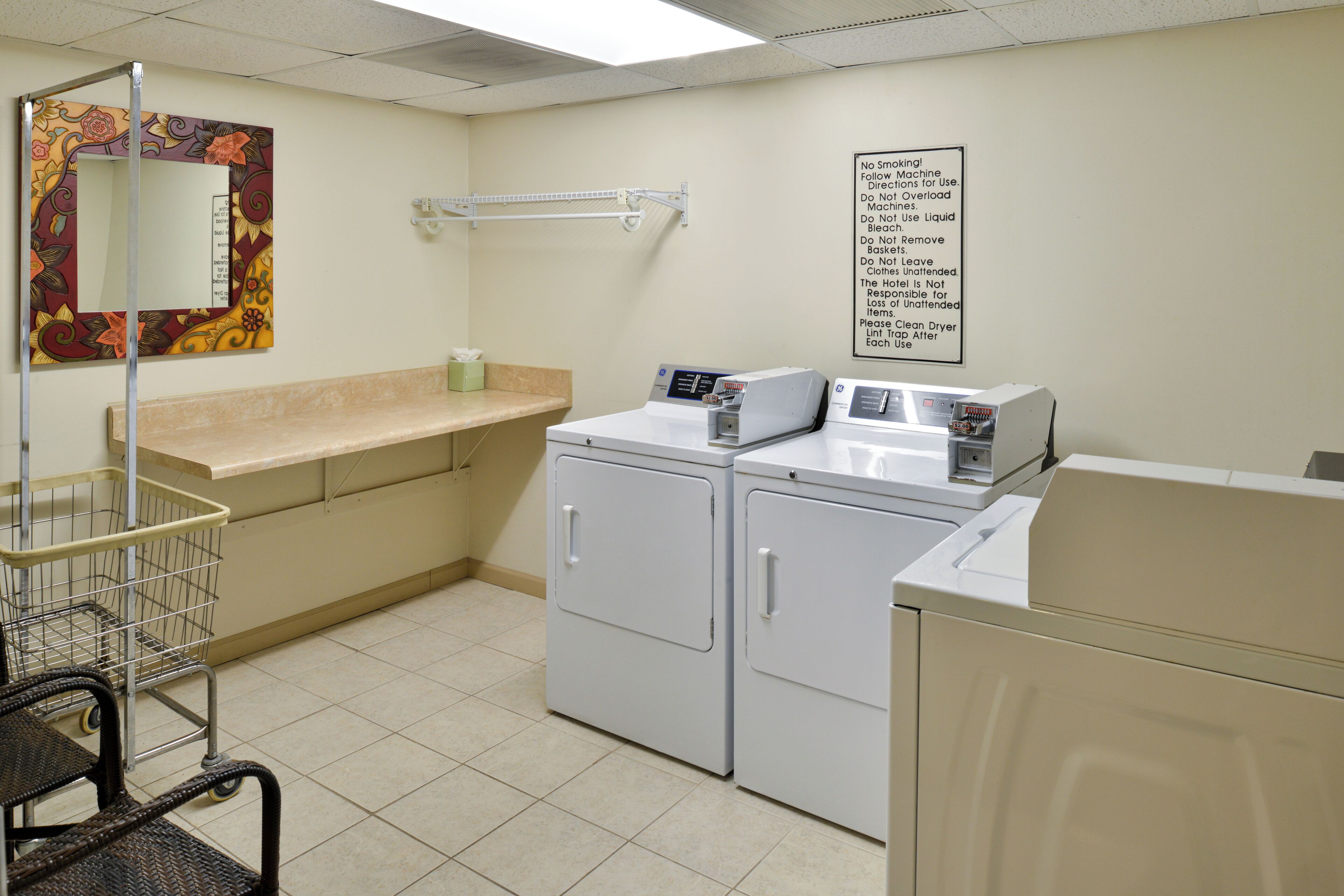 A laundry room with a washing machine, dryer, and a cart.