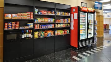 A vending machine stocked with snacks and beverages, a microwave, and a Coca-Cola refrigerator in a public area.