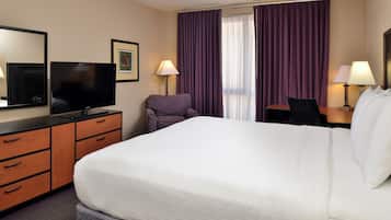 Une chambre d’hôtel avec un grand lit, un téléviseur à écran plat, un bureau avec une chaise et deux lampes.