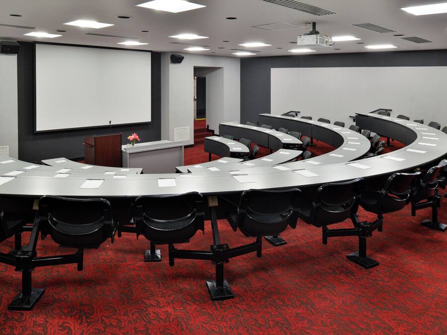 Une salle de conférence équipée d’une table incurvée, de chaises, d’un pupitre et d’un écran de projection.