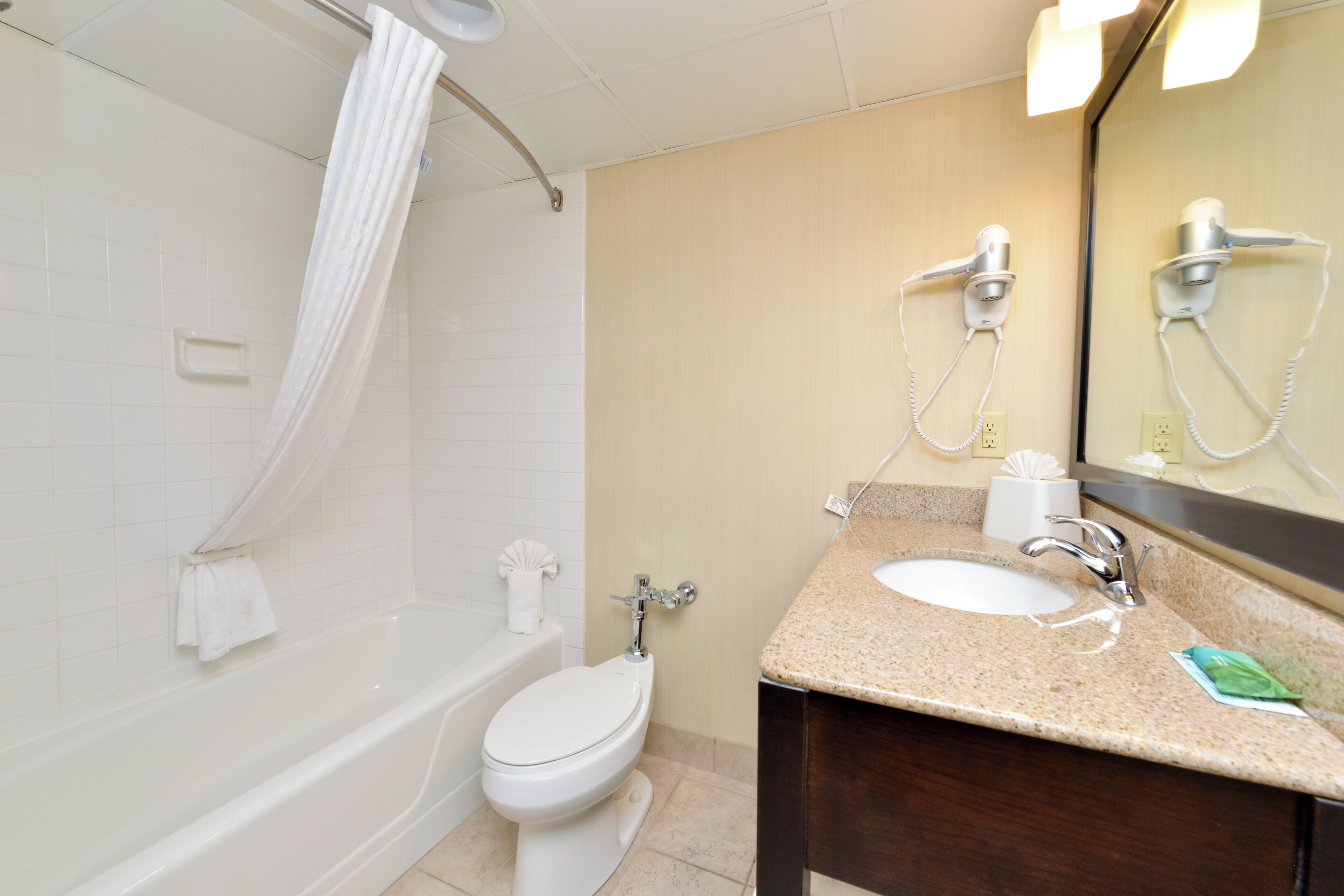 Un baño con bañera, inodoro, lavamanos y espejo.