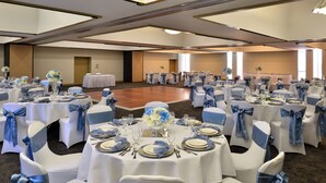 A banquet hall with round tables set for a formal event, each with white tablecloths and blue chair covers. - Hawthorne Inn and Conference Center (Winston-Salem)