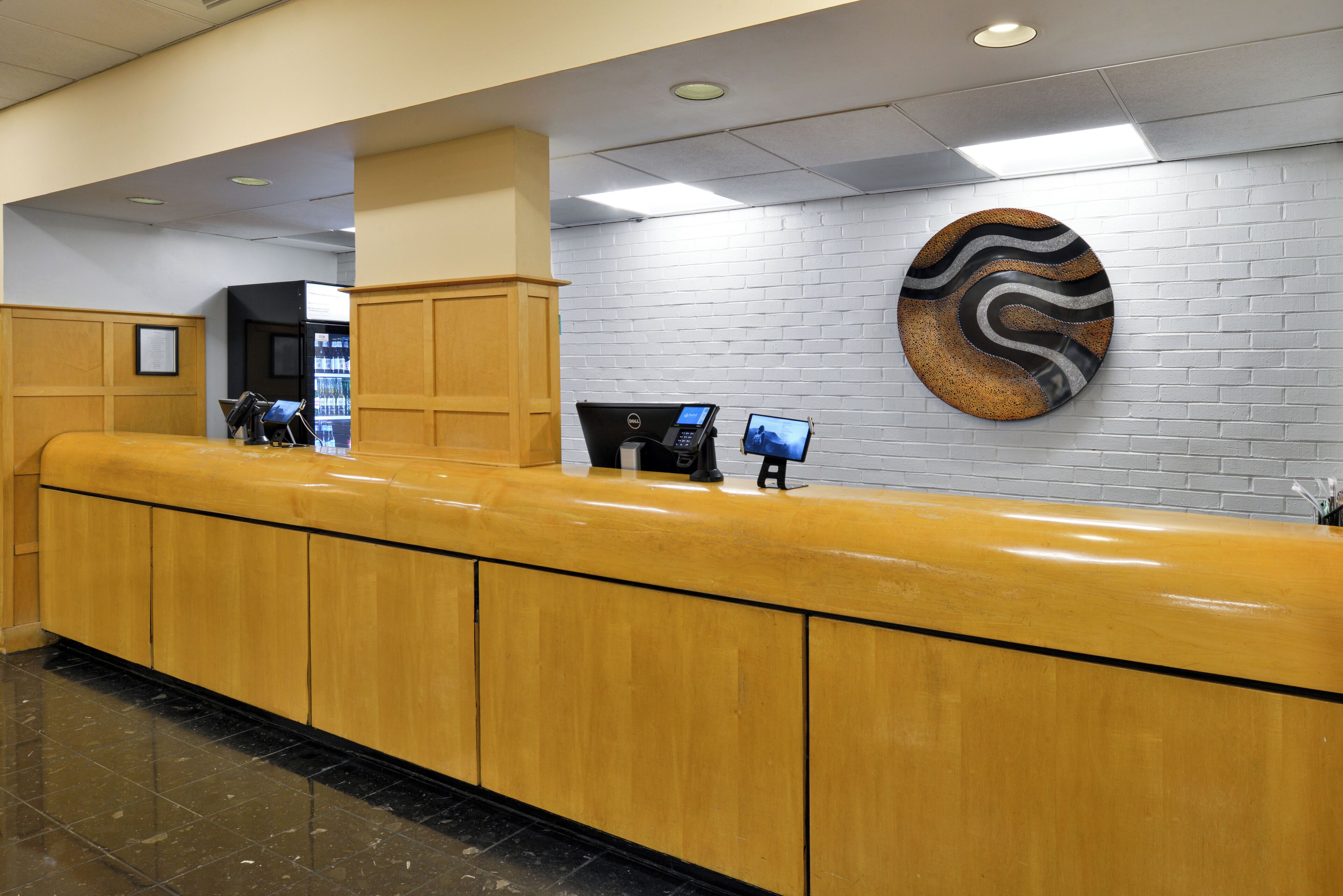 A reception desk with a wooden counter, a computer, and a monitor.