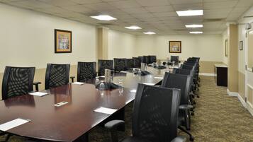 A conference room with a long table, multiple chairs, and framed pictures on the walls.