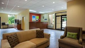 A lobby with a sofa and armchair, a reception desk, and a view of the outdoors.