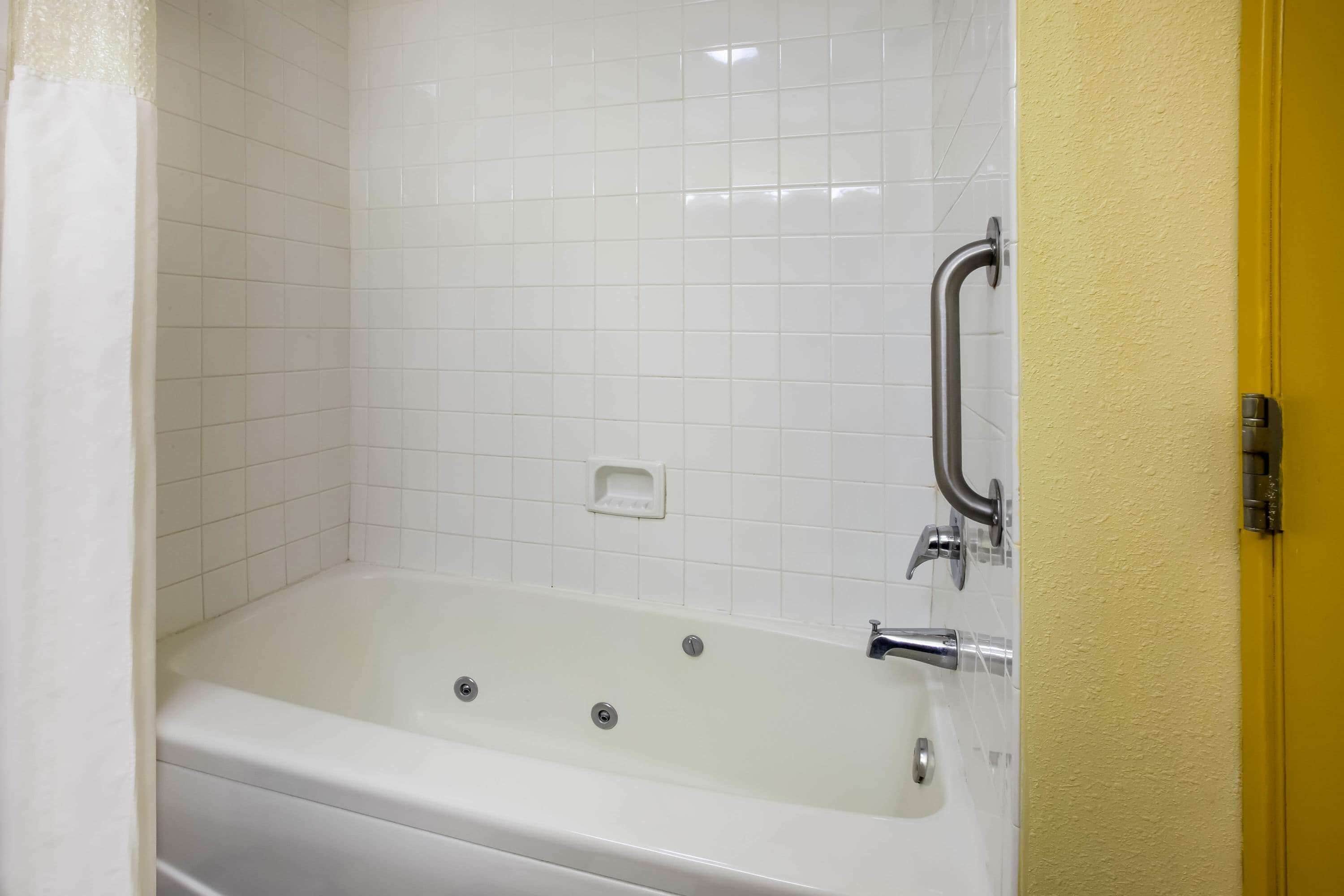 Una bañera blanca con ducha y jabonera.
