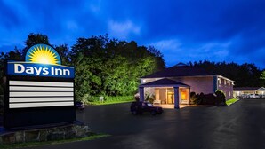 A Days Inn sign with a sun logo, a parking lot, and a building with a porch.
