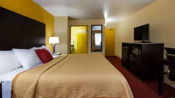 A hotel room with a bed, a TV, a desk, and a microwave.