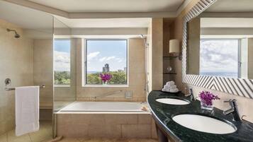 Une salle de bain moderne avec une douche à parois de verre, une grande baignoire, deux lavabos et un grand miroir.
