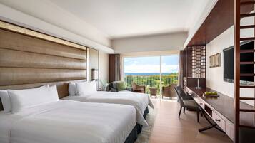Una habitación de hotel con dos camas, un escritorio, un televisor y un balcón con vistas.