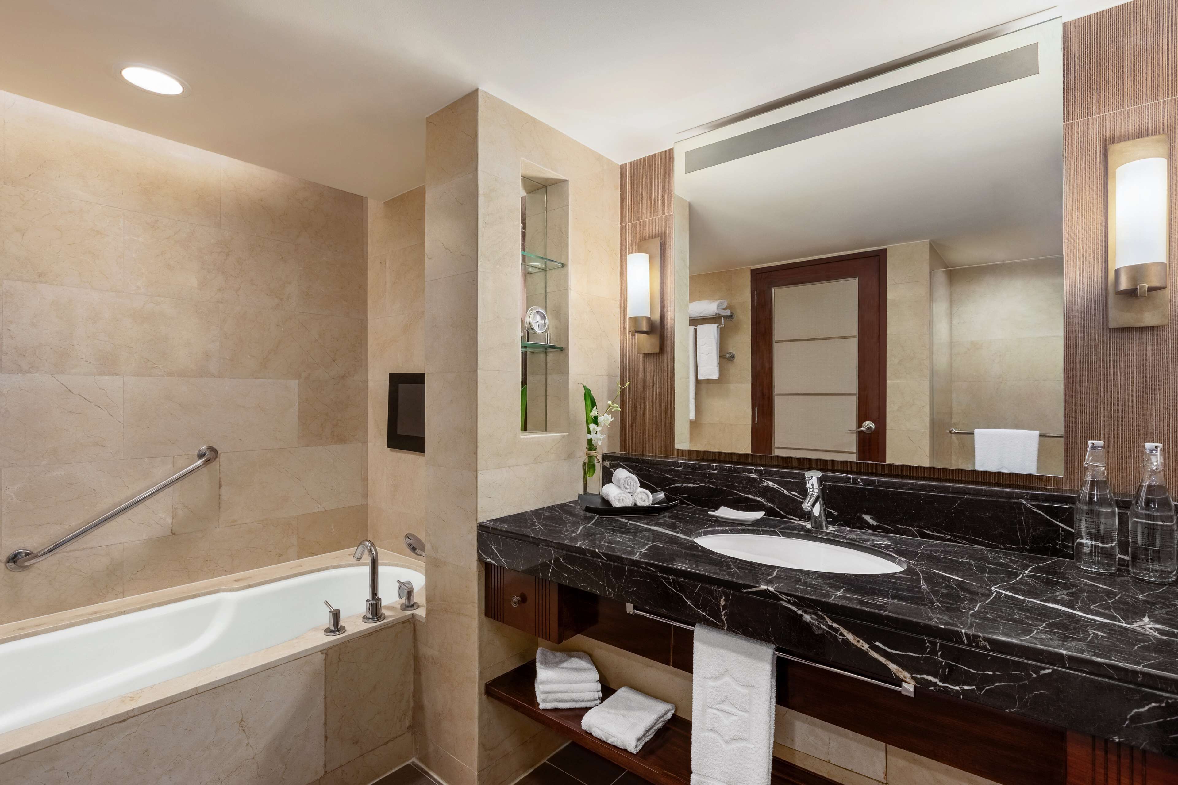 A modern bathroom with a marble sink, a bathtub, and a large mirror.