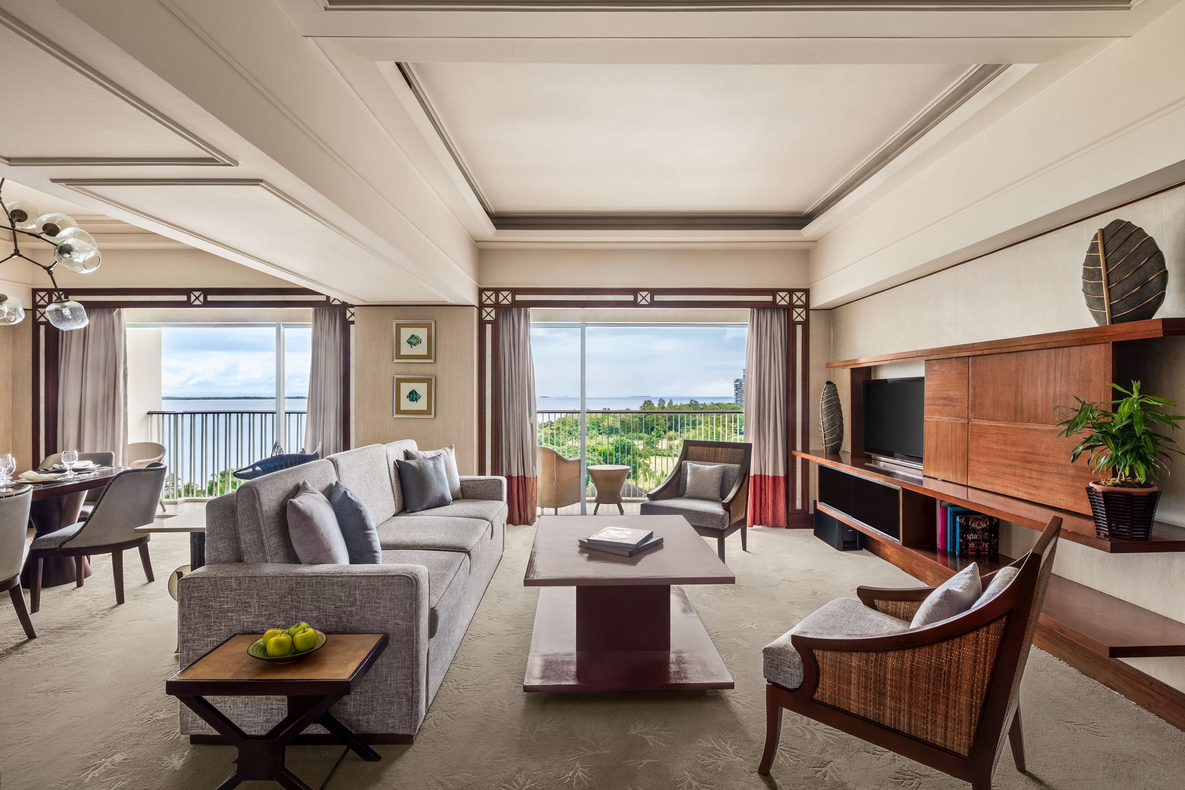 Un salon spacieux comprenant un canapé, des fauteuils, une table basse et un téléviseur. Il y a également un balcon avec vue sur l’extérieur.