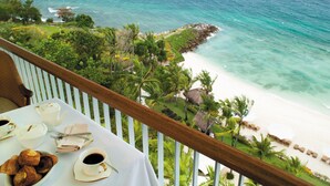 A balcony with a table set for breakfast overlooking a beach and ocean. - Shangri-La Mactan, Cebu (Lapu-Lapu)