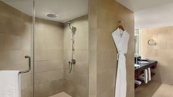 A modern bathroom with a glass-enclosed shower, a vanity with a mirror, and a robe hanging on a rack.