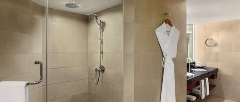 Une salle de bain moderne avec une douche à parois de verre, un meuble-lavabo avec un miroir et un peignoir suspendu à un porte-serviettes.