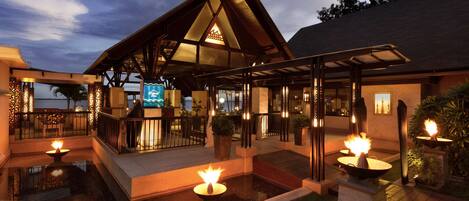 A modern hotel with a covered outdoor area, a pool, and multiple fire pits.